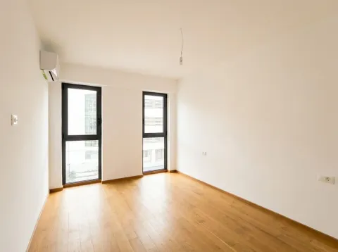 Prazna soba sa bijelim zidovima, drvenim podom i dva prozora. - image 11