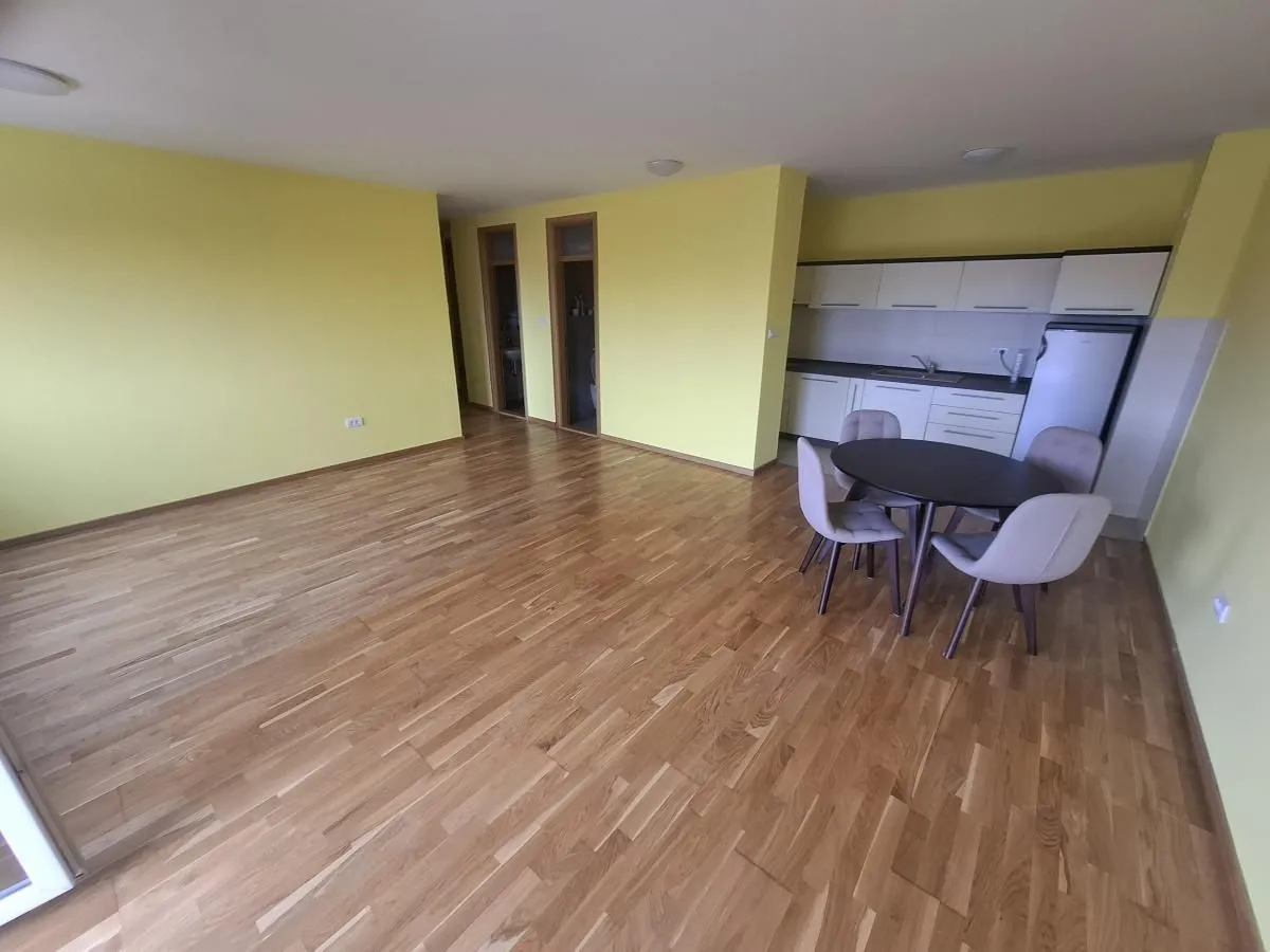 Prostrana dnevna soba sa trpezarijom i kuhinjom u uglu.