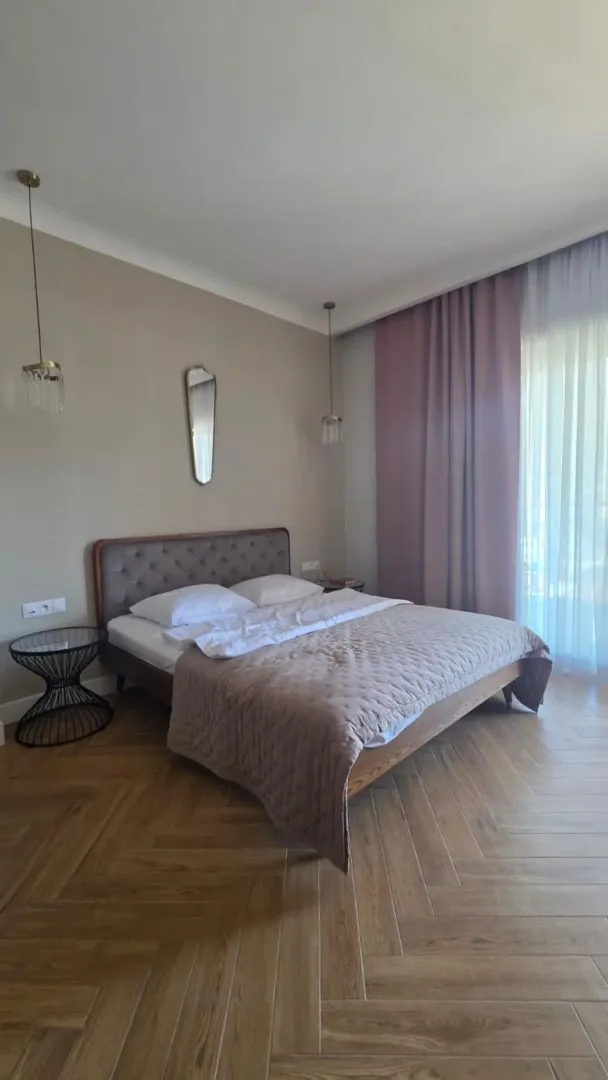 Moderna spavaća soba sa bračnim krevetom i parketom.