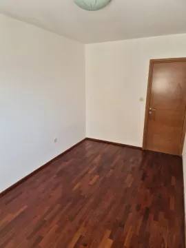 An empty room with dark parquet flooring and a wooden door. - image 9