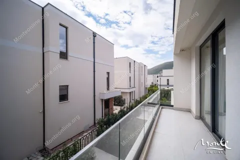 Moderan balkon sa staklenom ogradom i pogledom na okolne zgrade i brda. - image 35