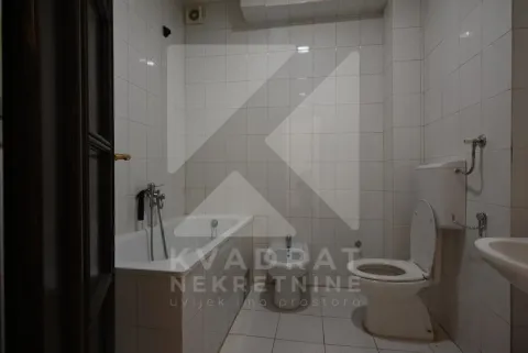 Bathroom lined with white tiles featuring a bathtub and a toilet. - image 19