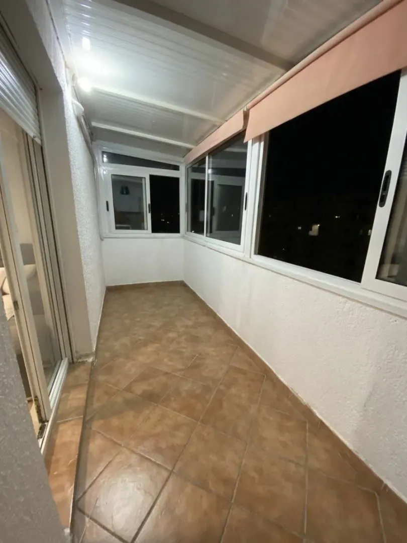 Zastakljeni balkon sa keramičkim pločicama na podu.