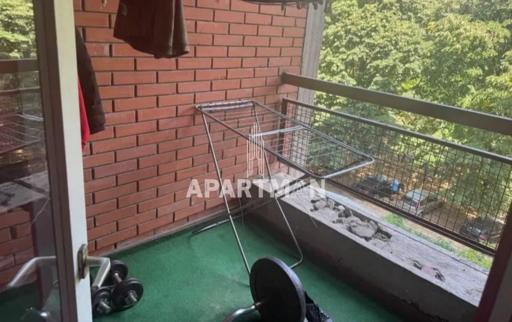 Balkon sa podnom oblogom nalik veštačkoj travi, stalkom za sušenje veša i fitnes opremom.