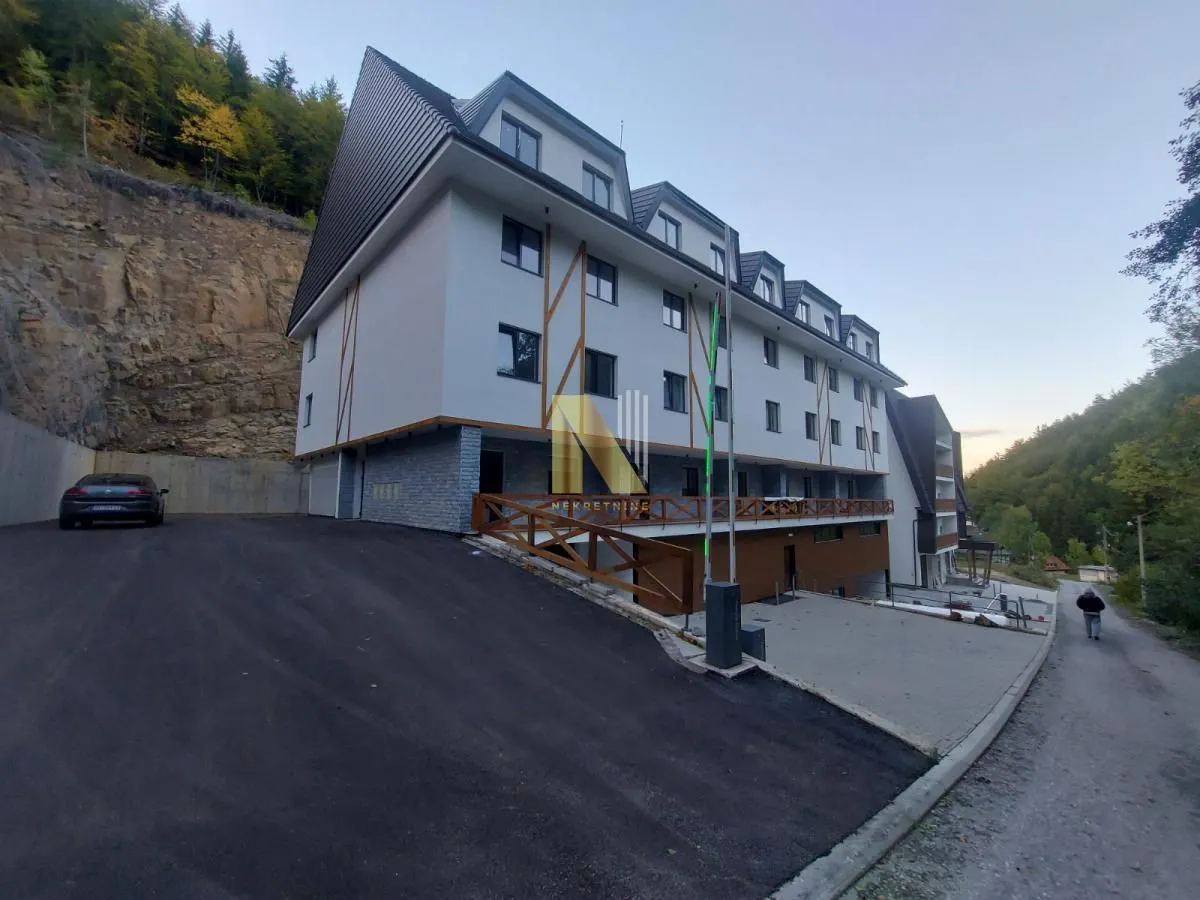 Spoljašnji izgled moderne stambene zgrade sa prilazom i parkingom.