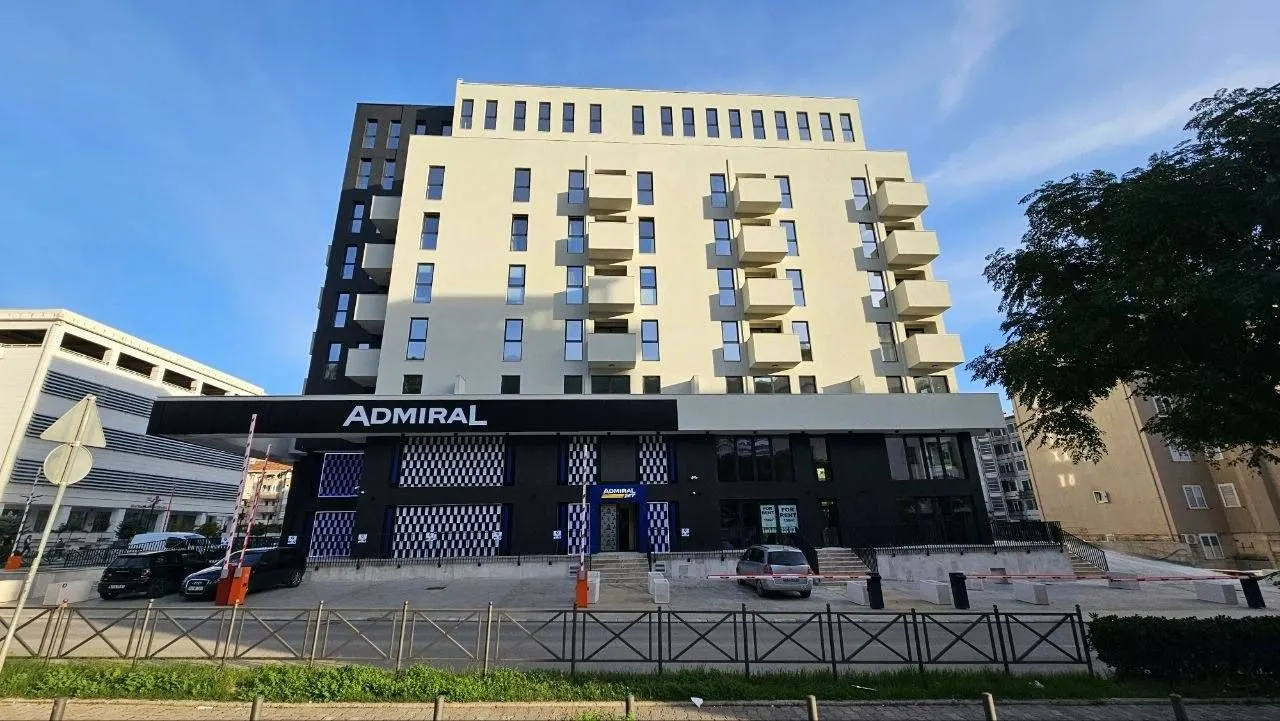 Eksterijer moderne višespratne stambeno-poslovne zgrade sa parkingom u prizemlju.