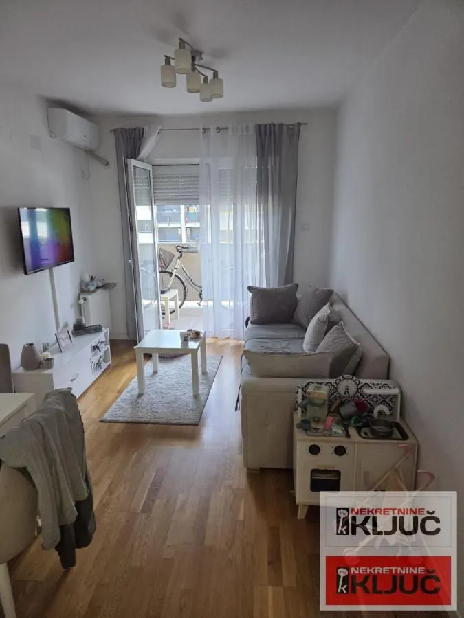 Dnevna soba sa garniturom, TV-om i izlazom na terasu.