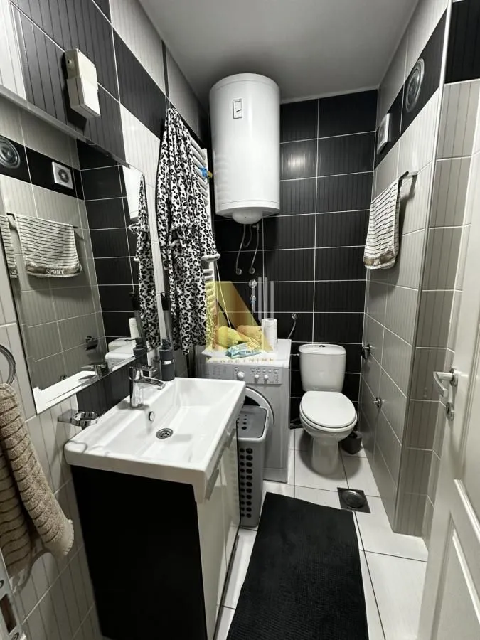 Manje kupatilo sa umivaonikom, WC šoljom, veš mašinom i bojlerom.