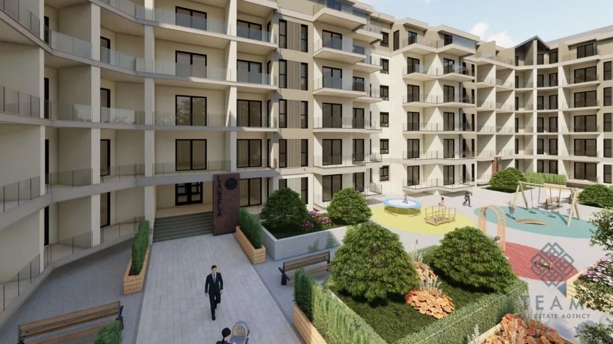 Pogled na spoljašnjost moderne stambene zgrade sa uređenim dvorištem i igralištem.