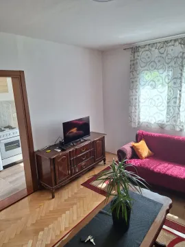 Living room with a sofa, TV cabinet, and a view into the kitchen. - image 2