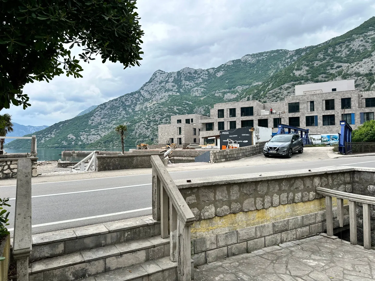 View of the surrounding buildings, road, and mountain landscape near the water.