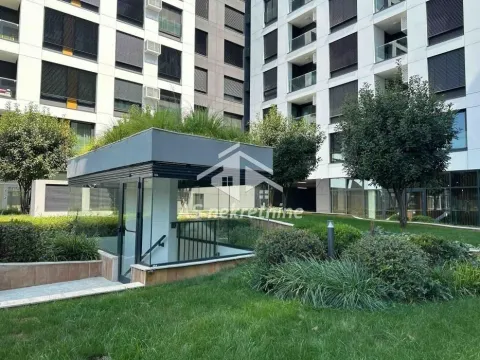 Dvorište sa uređenom zelenom površinom i modernom stambenom zgradom u pozadini. - image 23