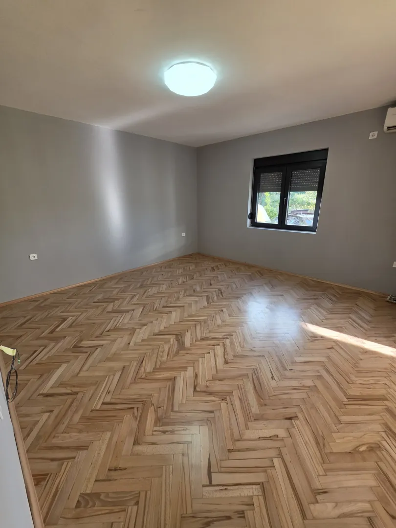 Empty room with parquet flooring and grey walls.
