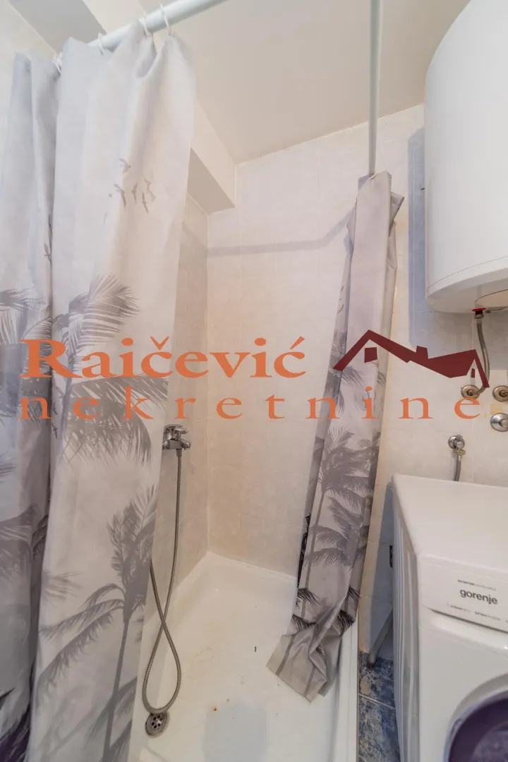 Small bathroom with a shower cabin and washing machine.