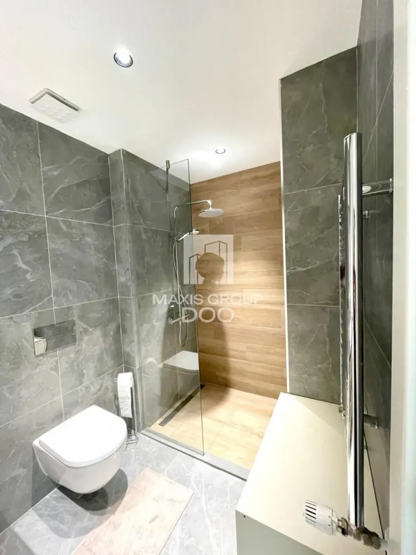 Modernly equipped bathroom with a walk-in shower and a wall-mounted toilet.