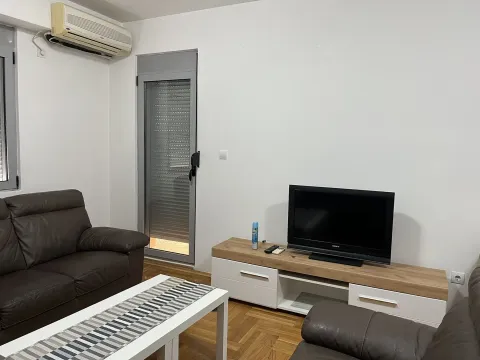 A living room with a leather sofa, a TV on a stand, and an air conditioner. - image 2