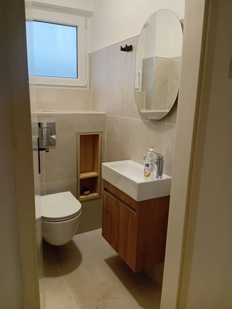 Manje moderno opremljeno kupatilo sa umivaonikom i toaletom.