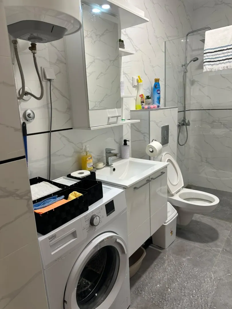 Modernly equipped bathroom with a washing machine and shower cabin.