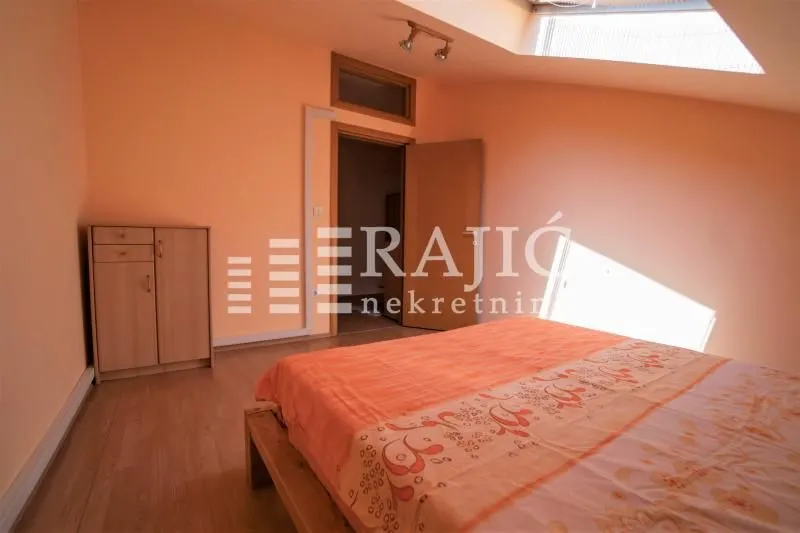 Attic bedroom with a double bed and a wooden chest of drawers.