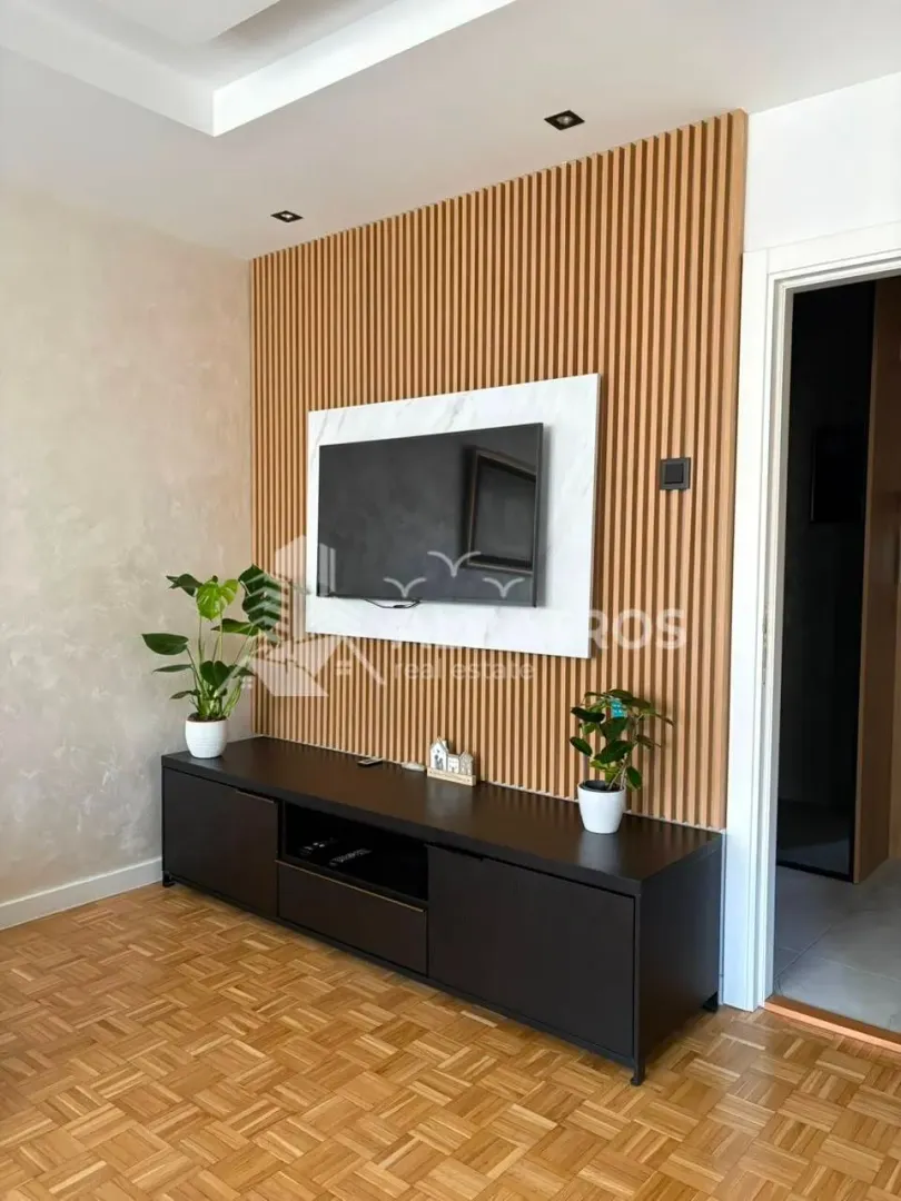 Living room with a TV unit and a wooden wall panel.