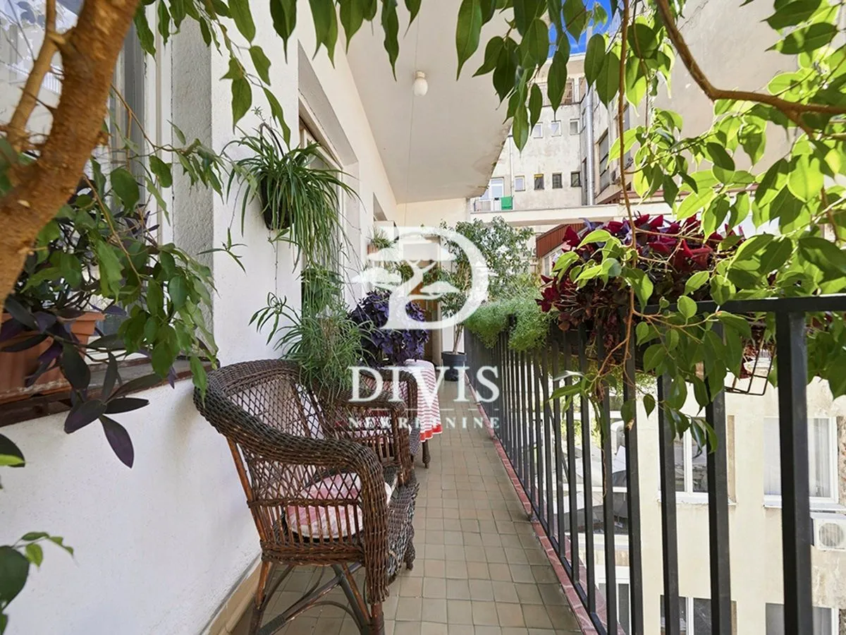 Dugi balkon sa pletenim stolicama i dosta zelenila.