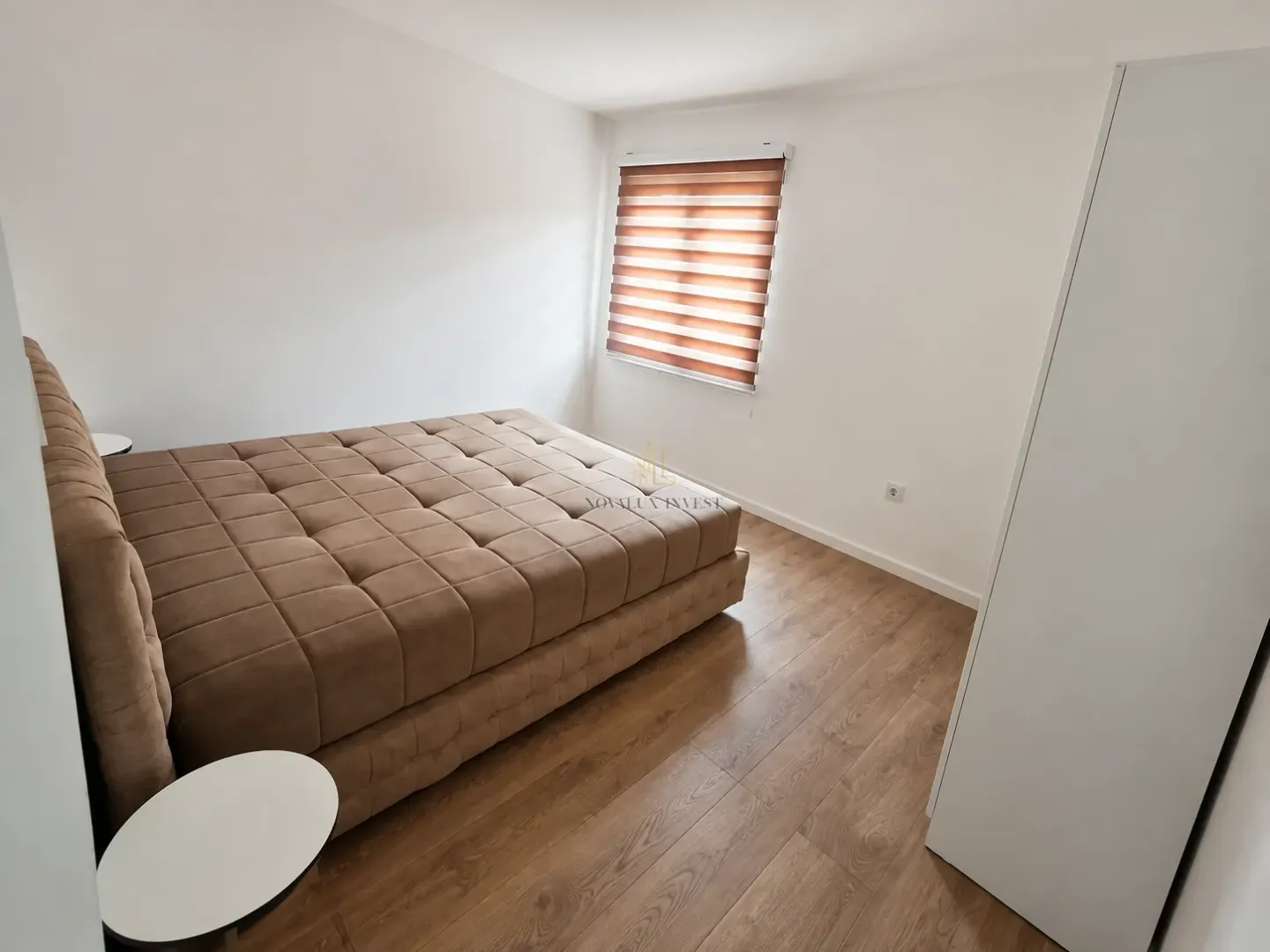 Bedroom with a double bed, white wardrobe, and wooden flooring.
