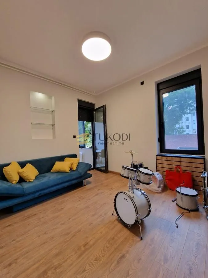 Living room with a blue sofa and drums on the floor.