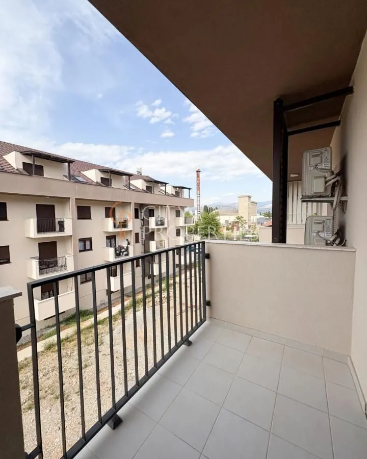 Manji popločani balkon sa ogradom i pogledom na naselje.