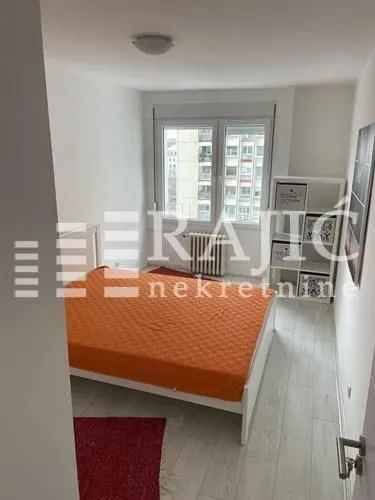 Furnished bedroom with a double bed and a shelving unit.