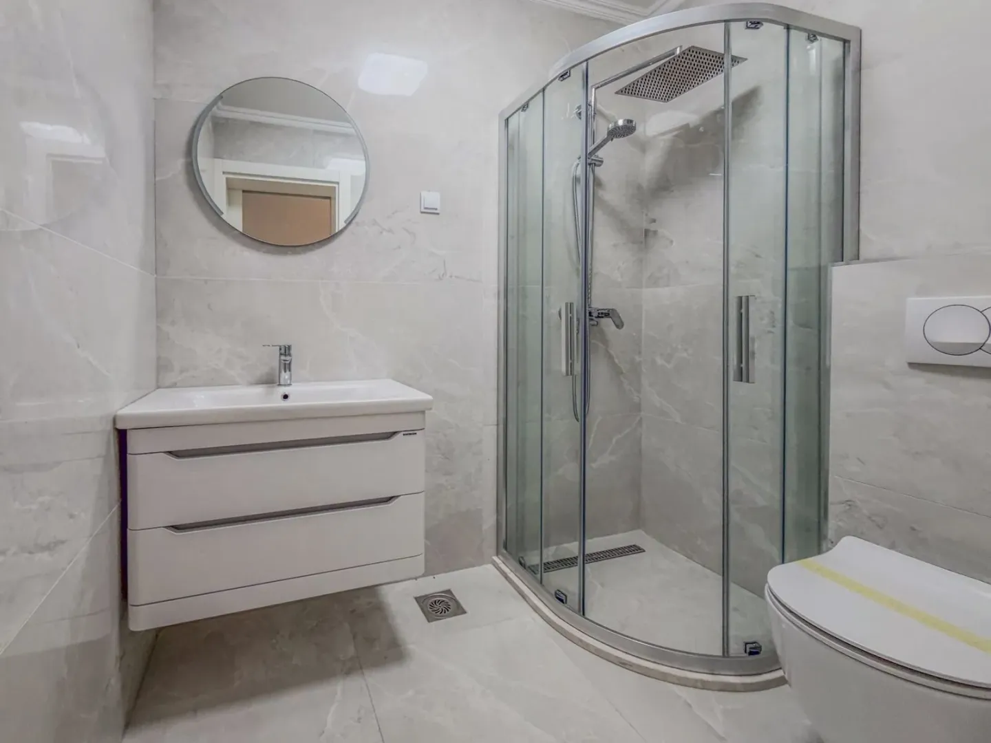Moderno opremljeno kupatilo sa tuš kabinom, umivaonikom i WC šoljom.