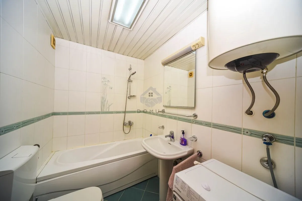 Bathroom equipped with a bathtub, washbasin, toilet, and water heater.