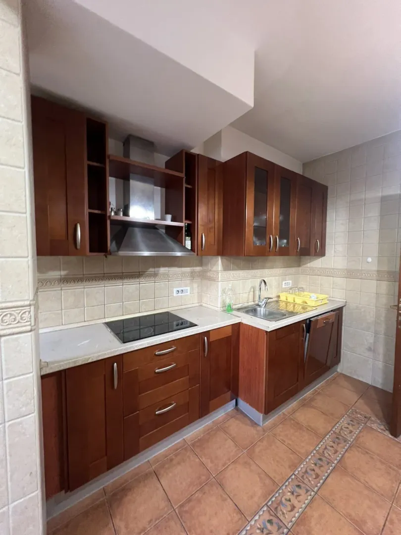 Kitchen with wooden cabinets, a built-in cooktop, and a range hood.