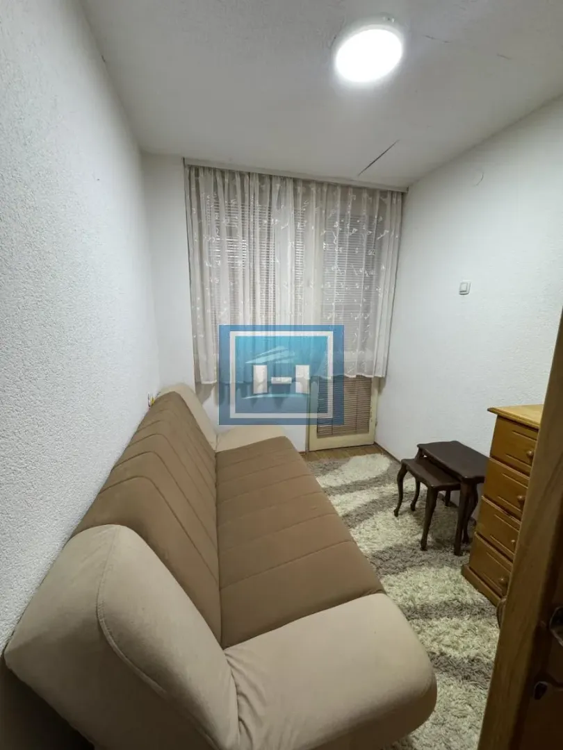 Small living room with a pull-out sofa and a window with curtains.