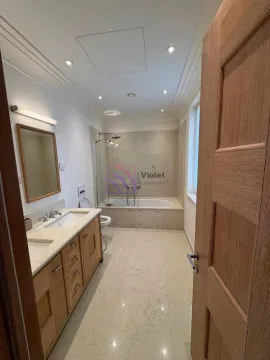 Spacious bathroom with a wooden vanity, double sinks, a bathtub, and a glass shower partition. - image 10
