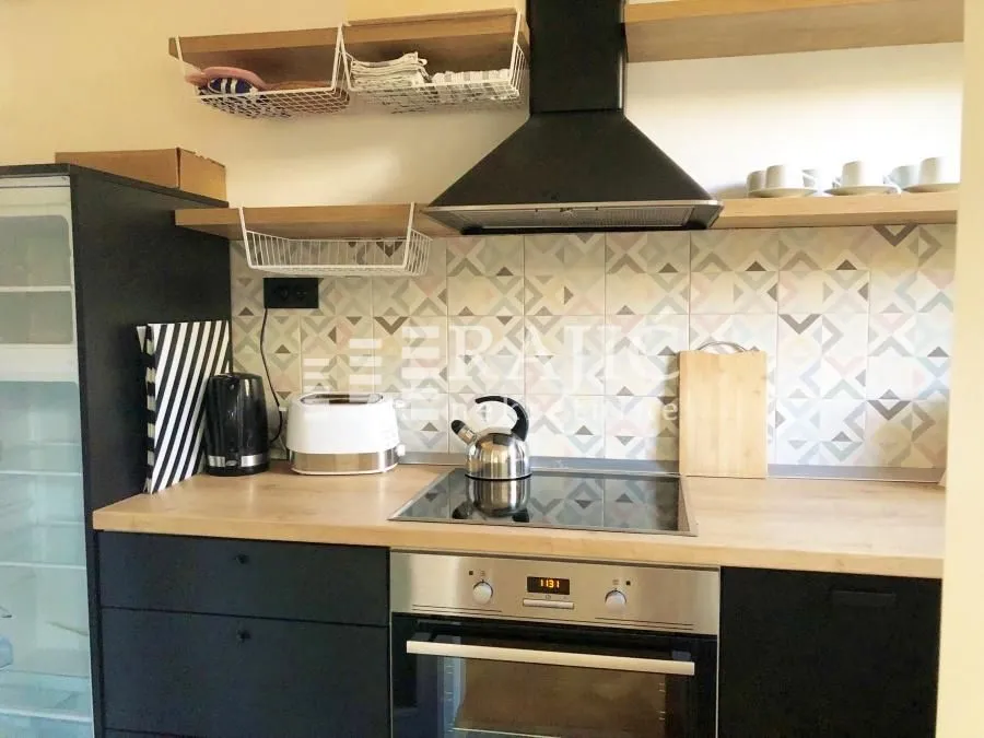 Modern kitchen with built-in cooktop, oven, and wooden elements.