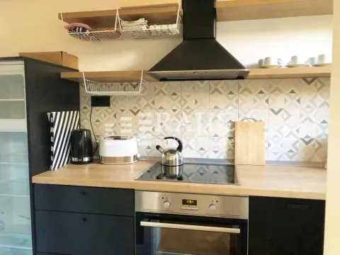 Modern kitchen with built-in cooktop, oven, and wooden elements. - image 2