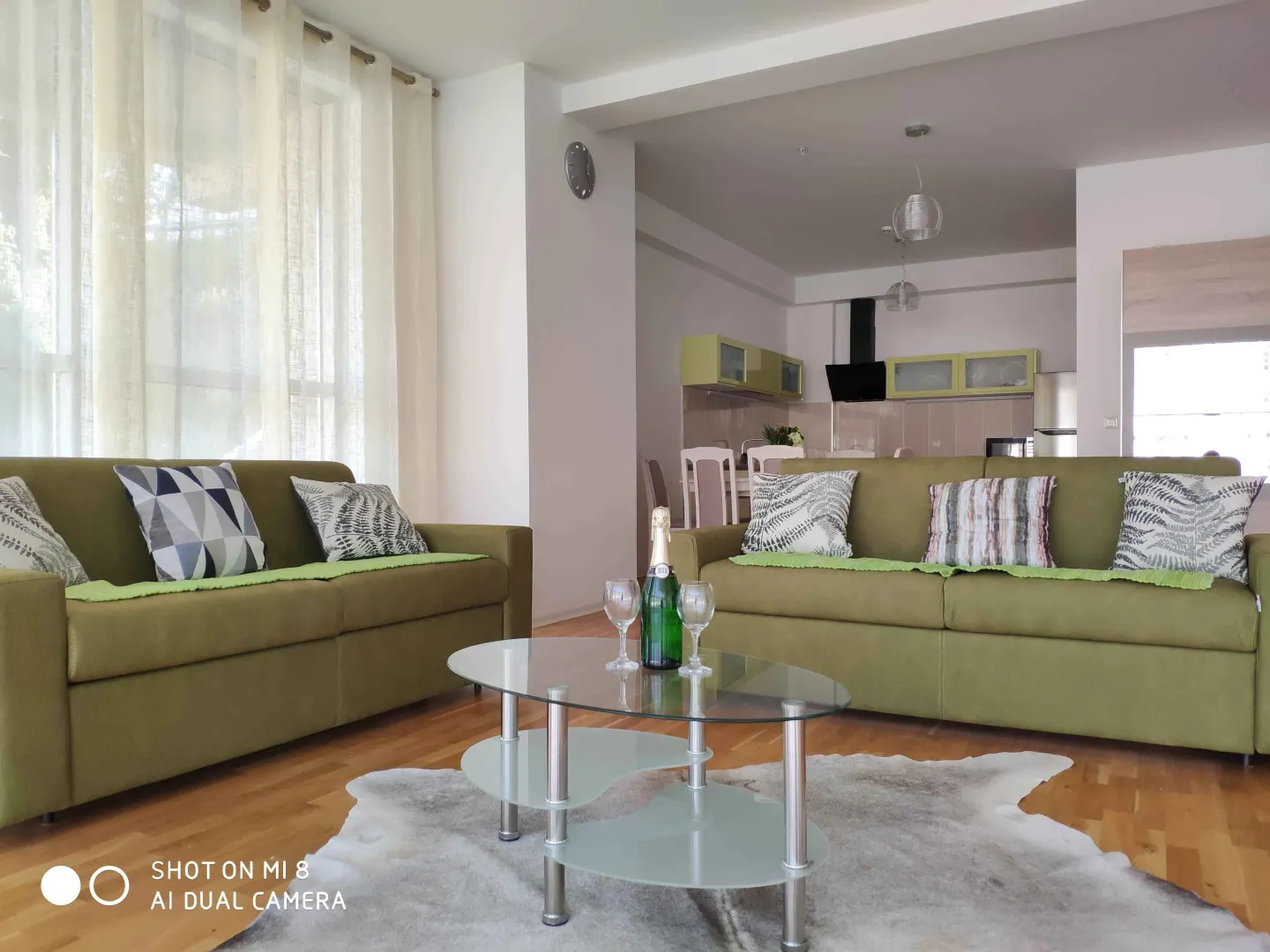 Bright living room with green sofas and a glass coffee table.