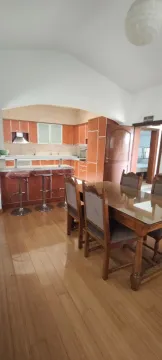 Dining area with a wooden table and chairs overlooking the kitchen with a breakfast bar. - image 10