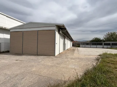 Exterior of a warehouse building with roller doors and a concrete plateau. - image 5