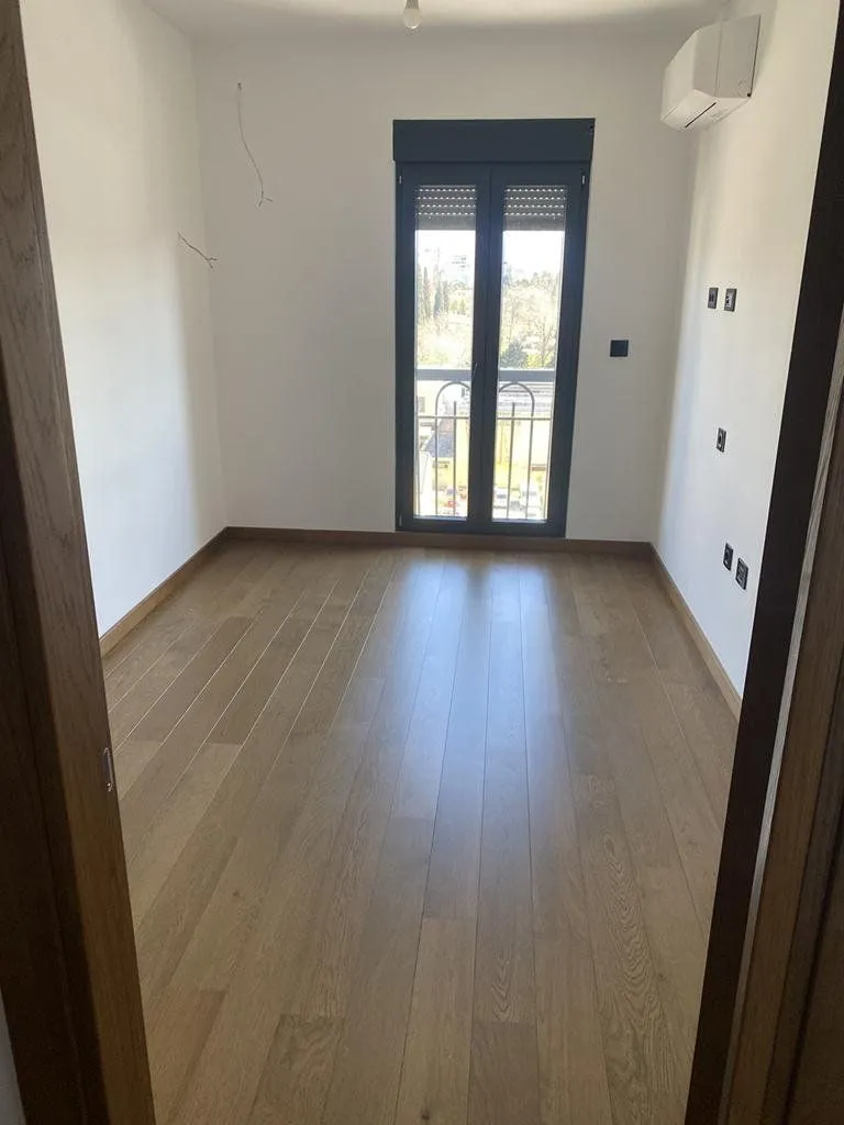Empty room with parquet flooring and balcony doors.