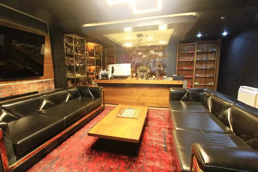 Spacious living room with black leather sofas and a wooden coffee table.