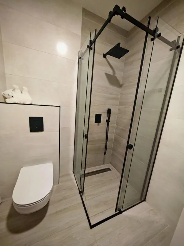 Moderno opremljeno kupatilo sa tuš kabinom i ugradnom šoljom.