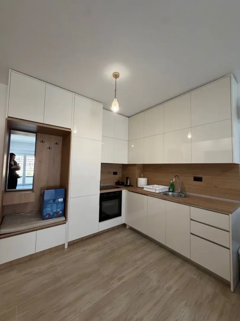 Modern white kitchen with wooden elements and a built-in cabinet with a mirror.