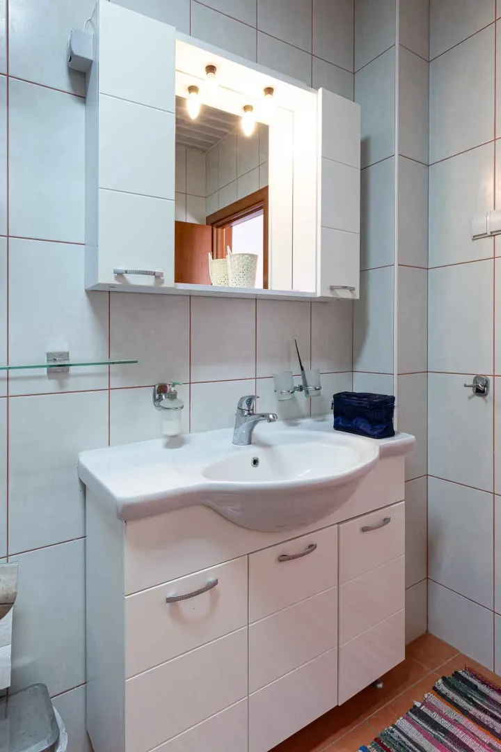 Kupatilo sa umivaonikom, ormarićem i ogledalom.
