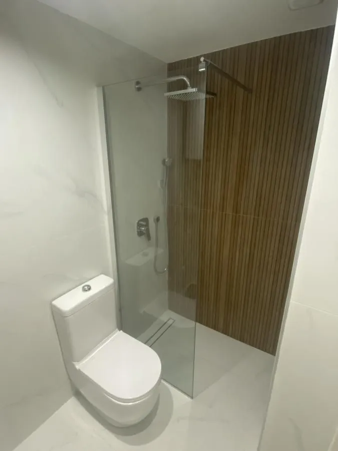 Moderno opremljeno kupatilo sa tuš kabinom i belim toaletom.