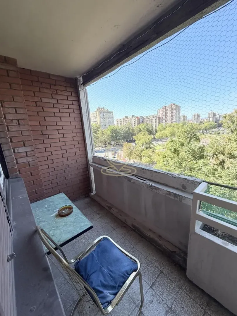 Manji zatvoreni balkon sa stolom i stolicom i pogledom na grad.