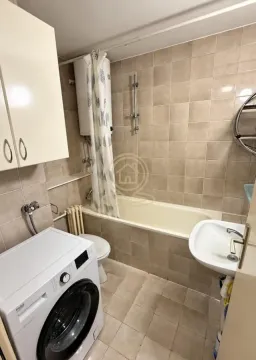 Bathroom equipped with a bathtub, sink, toilet, and washing machine. - image 10
