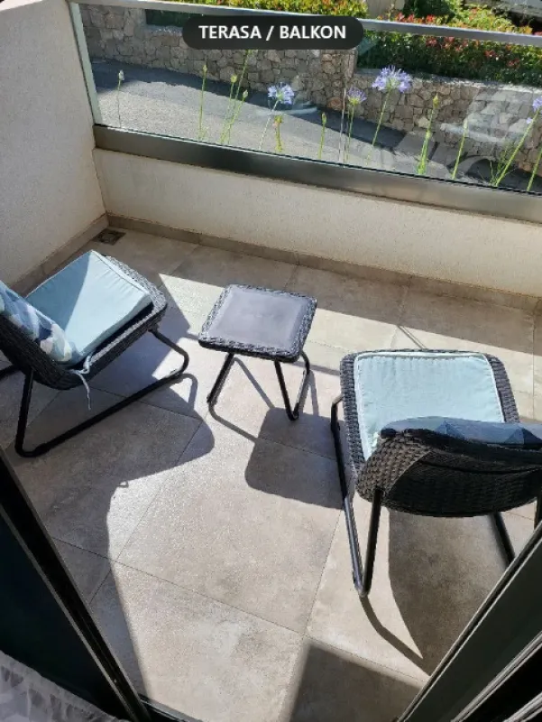 Manja opremljena terasa sa garniturom za sjedenje i staklenom ogradom.
