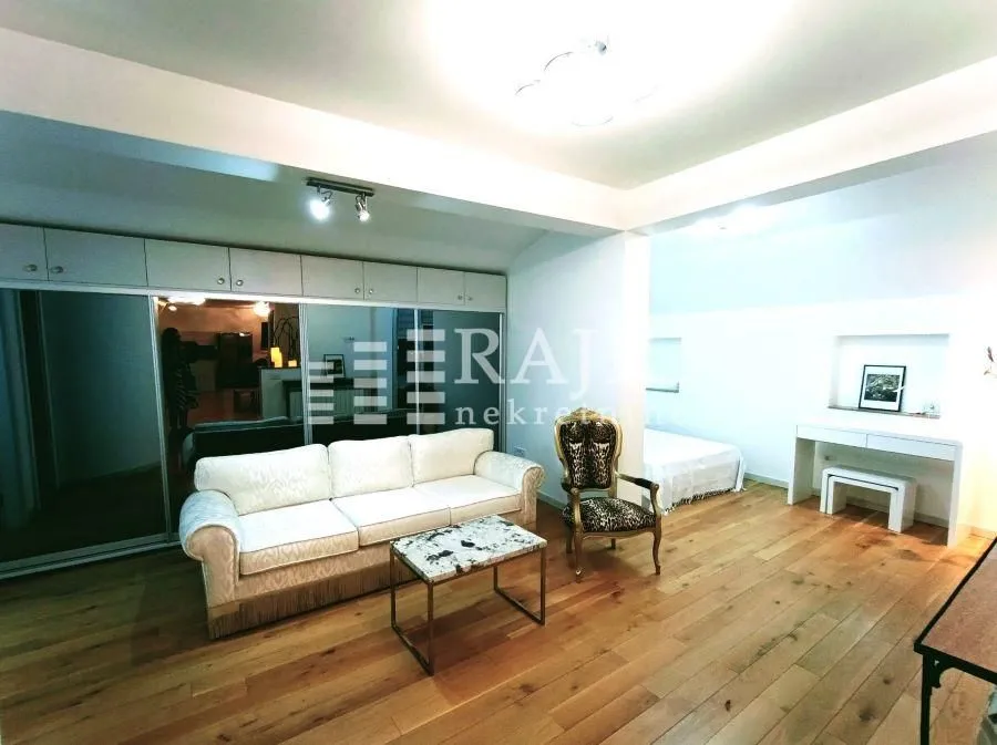 Spacious living room with sofa and wooden floor.