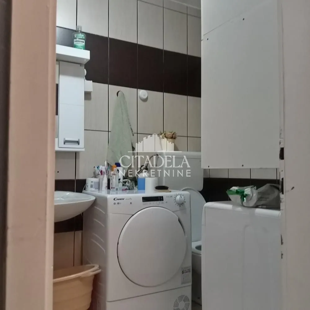 Manje kupatilo opremljeno sanitarijama i veš mašinom.